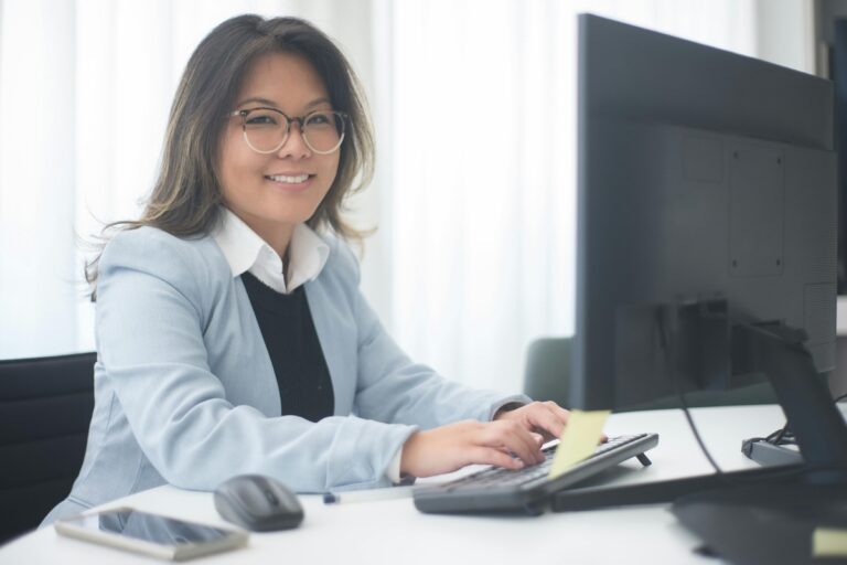 Faculty member seated at a desk in a well-lit office, reflecting balance, focus, and boundary setting in academic life.