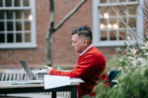 Faculty member working at a laptop with teaching materials and assignments, reflecting the impact of AI on faculty workload.